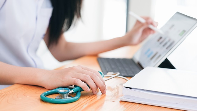 Doctor sitting at workplace and using laptop.